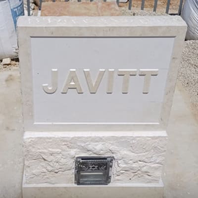 מצבה עם השם JAVITT על רקע גדר