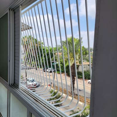 סורגים לבנים על חלון פתוח עם נוף חיצוני