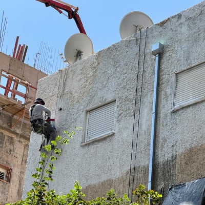 אדם עובד על קיר בניין עם ציוד טיפוס