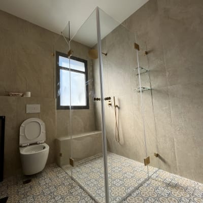 מקלחון זכוכית עם אביזרי זהב בחדר אמבטיה מודרני