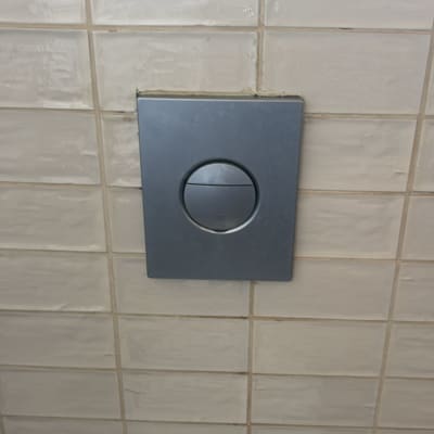 לחצן הדחה על קיר אריחים בחדר אמבטיה