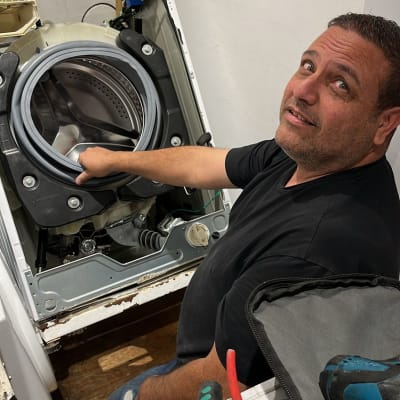 אדם מתקן מכונת כביסה עם כלים חשמליים