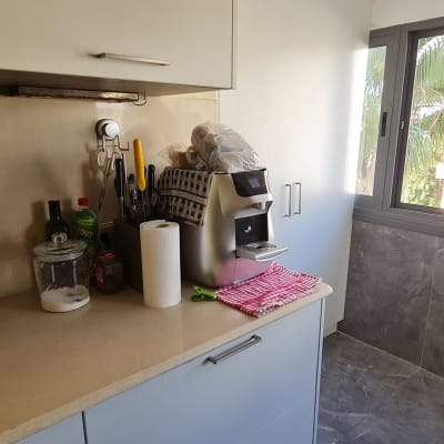 מטבח עם ארונות, מכונת קפה וכלי מטבח על השיש