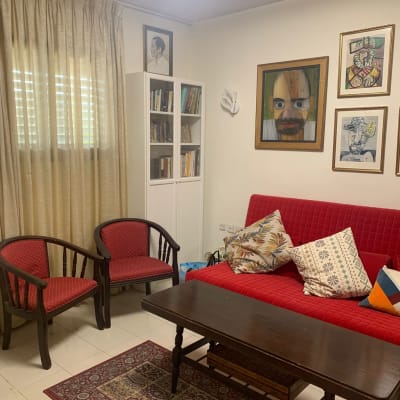 חדר מסודר עם ספה, כורסאות, שולחן וציורים על הקיר