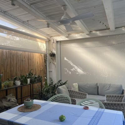 מרפסת עם סוכך, שולחן וכיסאות, צמחים מסביב