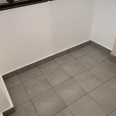 רצפה מרוצפת באריחים אפורים ליד קיר לבן