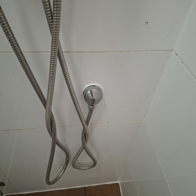 צינור מתכת במקלחת על רקע אריחים