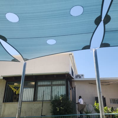 סוכך כחול מותקן מעל חצר בית עם אדם ברקע