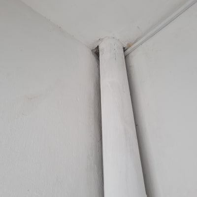 צינור לבן צמוד לקיר לבן בפינת חדר