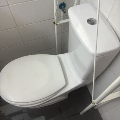 אסלה לבנה עם צינור מים בחדר אמבטיה