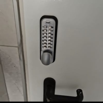 מנעול קוד על דלת לבנה עם ידית שחורה