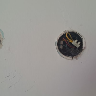 חוטי חשמל צבעוניים בקופסת חיבורים בקיר