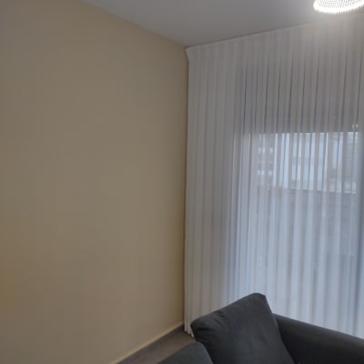 קיר צבוע עם וילון וספה בחדר מגורים