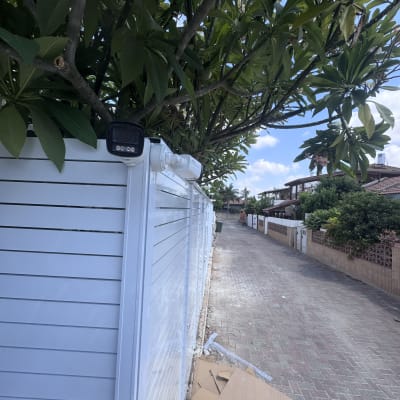 מצלמת אבטחה מותקנת על גדר ליד עץ