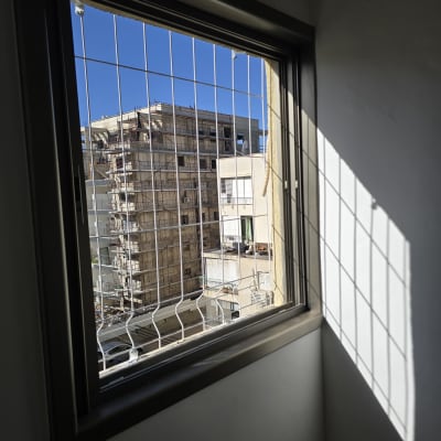 חלון עם סורגים המשקיף על בניין בשיפוצים