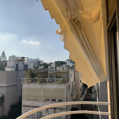 סוכך צהוב תלוי מעל מרפסת עם נוף עירוני
