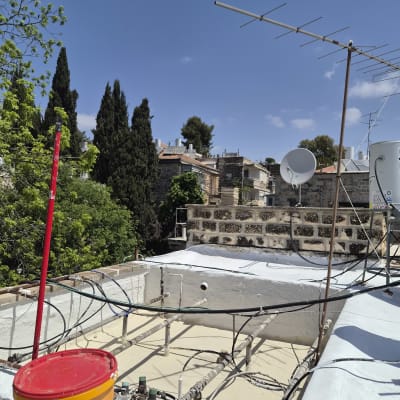 גג עם חומרי איטום ודלי צבע על רקע שמיים כחולים