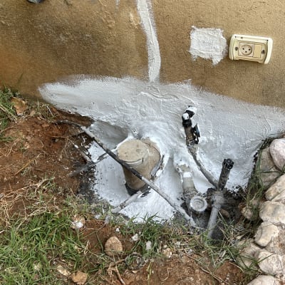 איטום צנרת עם חומר לבן על קיר חיצוני