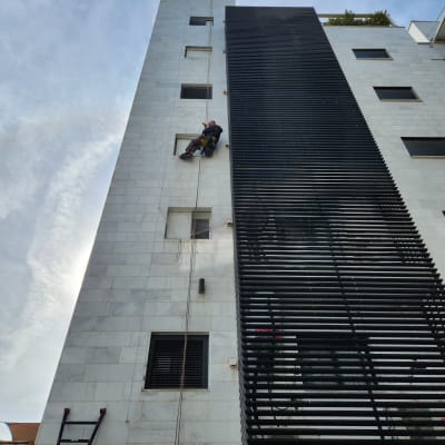 אדם תלוי על חבל על קיר בניין גבוה