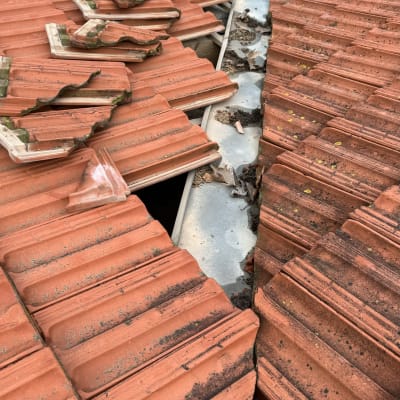 רעפים שבורים על גג רעפים אדום עם תעלה מתכתית