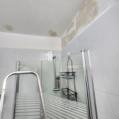 סולם מתכת ליד מקלחת עם תיקוני טיח בתקרה