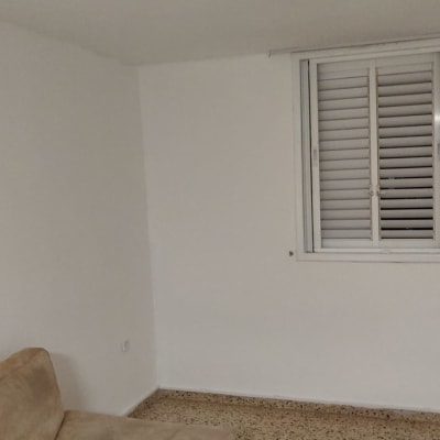 קיר צבוע בלבן עם חלון ותריסים