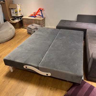 חדר עם ספה אפורה, כרית ומשחק ילדים על קופסה