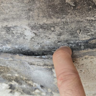 אצבע מצביעה על סדק וכשל בשכבת איטום בבטון
