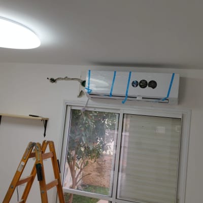 מזגן מותקן על קיר עם סולם ליד חלון