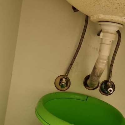 צנרת מתחת לכיור עם דלי ירוק