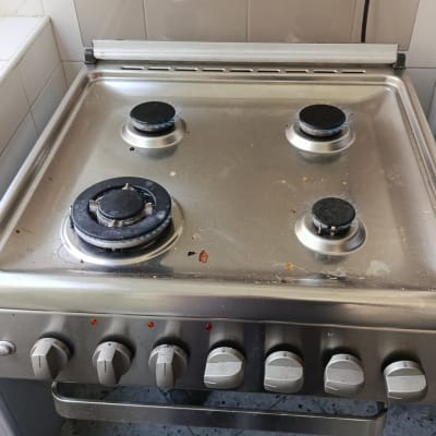 כיריים גז מנירוסטה עם ארבעה מבערים דולקים במטבח
