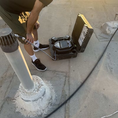 אדם משתמש בציוד לגילוי נזילות על גג