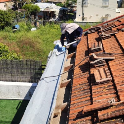 אדם עובד על גג רעפים עם כלי עבודה