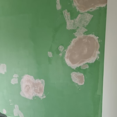 קיר ירוק עם תיקוני טיח בצבע בז