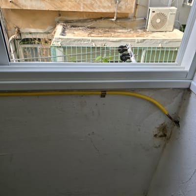 צינור גז צהוב מחובר לקיר ליד חלון פתוח