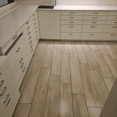 מטבח נקי עם ארונות לבנים ורצפת עץ