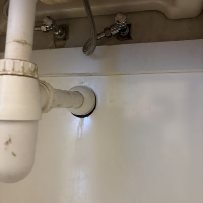 צנרת מתחת לכיור עם חיבורים ודליפה קלה