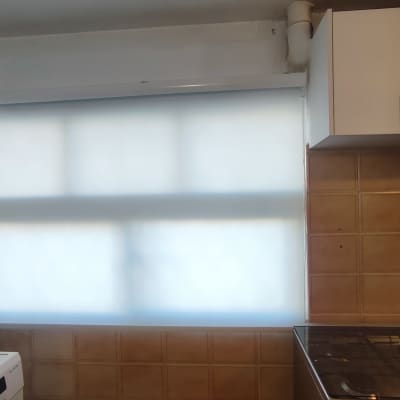 וילון גלילה לבן על חלון במטבח