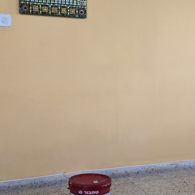 דלי צבע אדום על רצפה ליד קיר צבוע