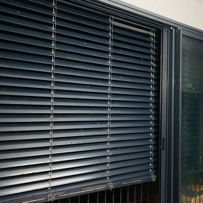 תריסים אופקיים כהים על חלון זכוכית