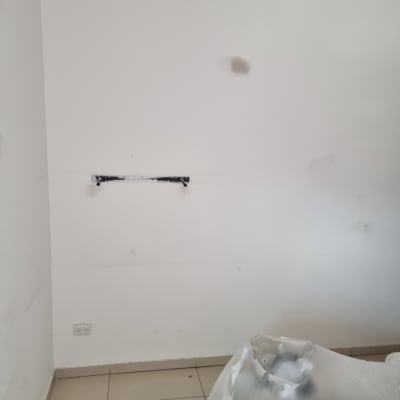 קיר לבן עם סימני תיקון וציוד מכוסה בניילון