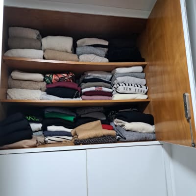 בגדים מקופלים בארון עץ פתוח עם מדפים