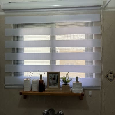 מדף עם קישוטים מעל כיור וחלון עם וילון