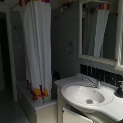 חדר אמבטיה עם וילון צבעוני ודלת ארון פתוחה