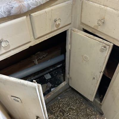 צנרת אינסטלציה שנחשפה מתחת לארון עץ ישן בבית