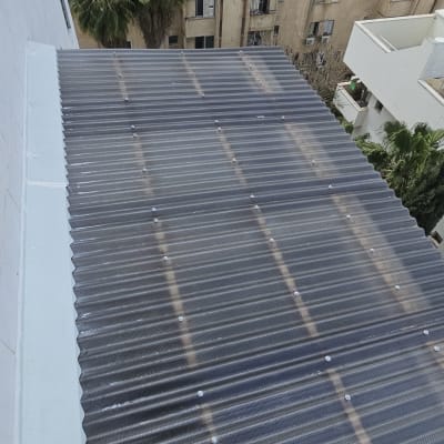 גג עם לוחות פלסטיק שקופים ונוף עירוני ברקע