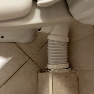 צינור גמיש מחובר לאסלה על רצפה מרוצפת