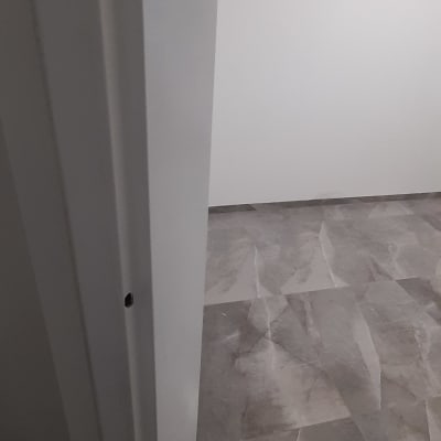 דלת צבועה בלבן עם קיר לבן ורצפה אפורה