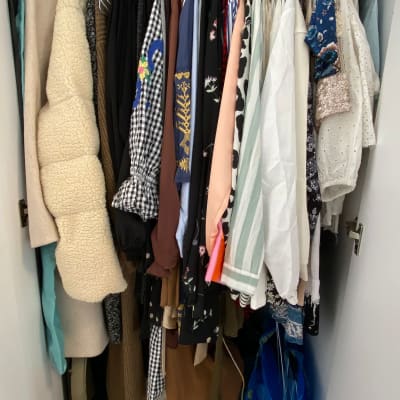 בגדים תלויים בארון על קולבים מסודרים בצפיפות