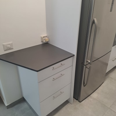 מקרר ליד ארונות מטבח עם משטח עבודה כהה